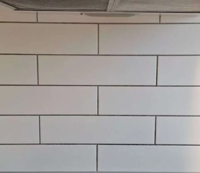 The same cooktop area after the white splashback and tile joints were cleaned
