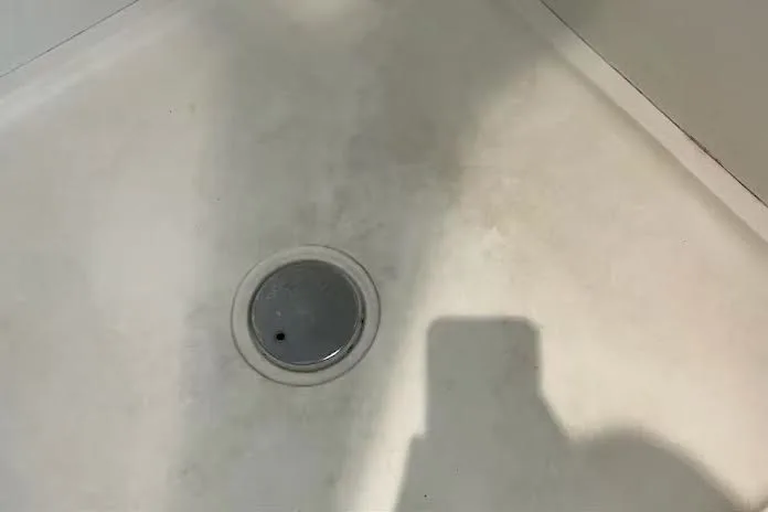 Shower tray before cleaning with residue around the drain
